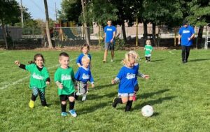 Kids playing soccer game outdoors in green field.