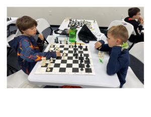 Two boys playing chess at a tournament.