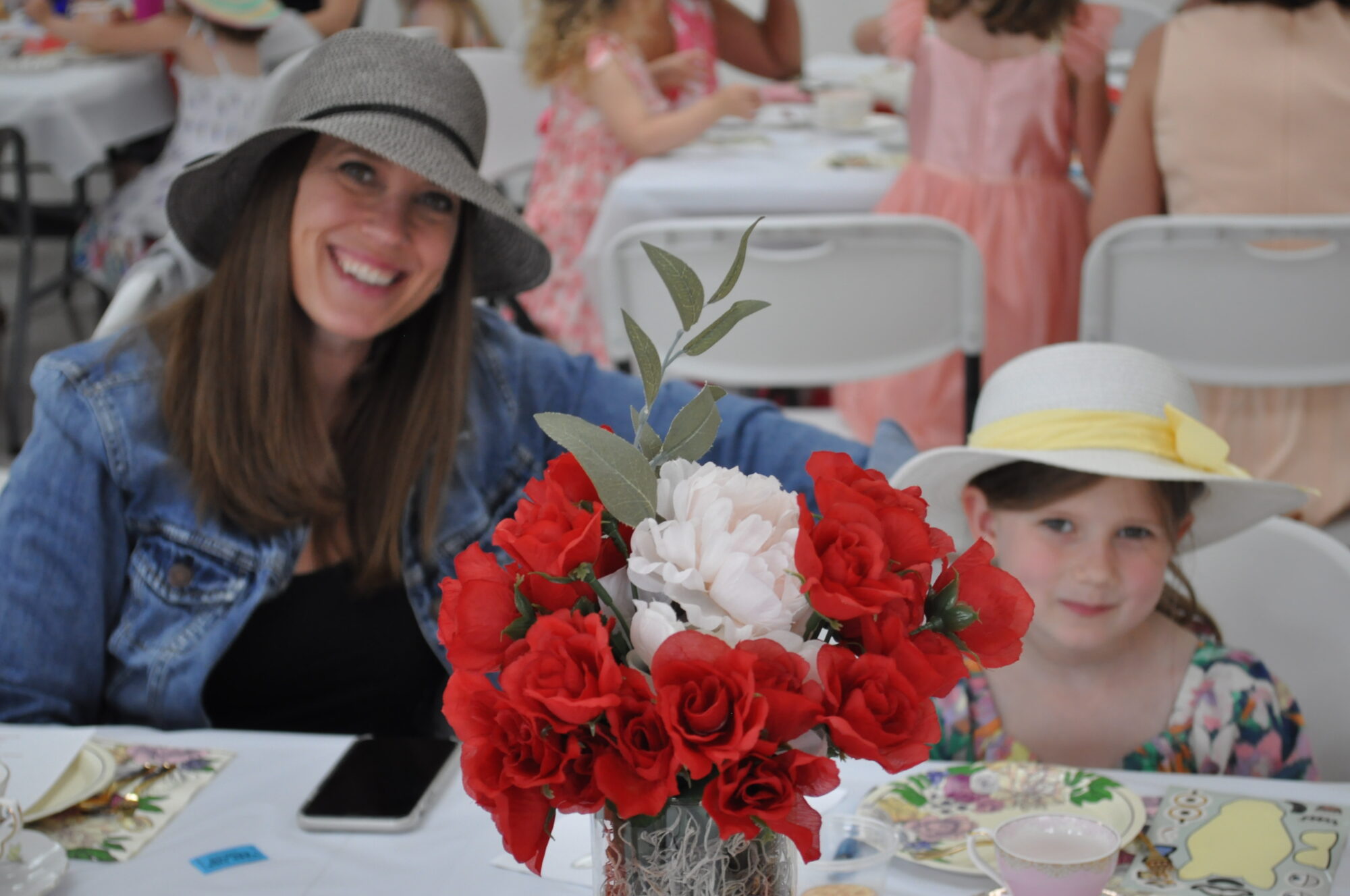 Woman and girl wearing hats at tea party.