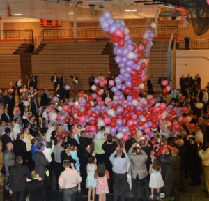 Balloon release in crowded indoor event.