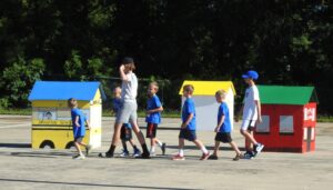 Children walking past model schoolhouses outdoors.