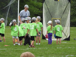 Kids in green jerseys at baseball practice.