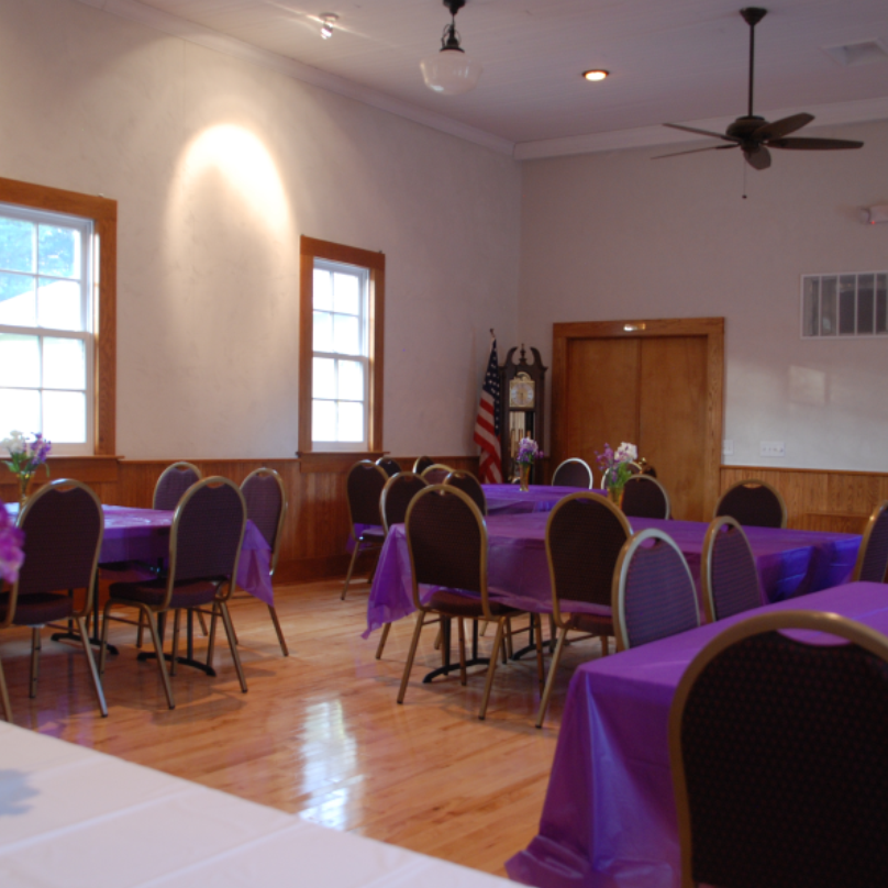 Empty event room with purple tablecloths.