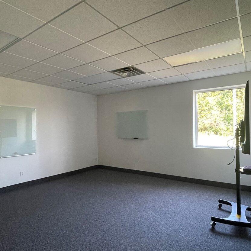 Empty classroom with whiteboards and TV stand.